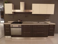 Cucina Astra modello DADA, con basi in rovere grigio e pensili in rovere poro aperto laccato bianco, a doppia profondità: 60 cm per le due basi laterali e 70 cm per la parte centrale con canale retrostante attrezzato. Top in Teknor e quarzo.